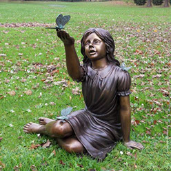 Bronzefigur - Sitzendes Mädchen mit Schmetterlingen -. Bronzefiguren und Gartenfiguren bei Kunsthandel Lohmann in Timmendorfer Strand.